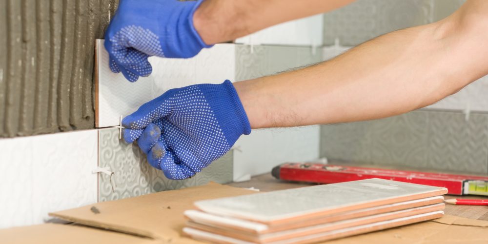 closeup-of-tiler-hand-laying-ceramic-tile-on-wall-EEZMDHM (2)